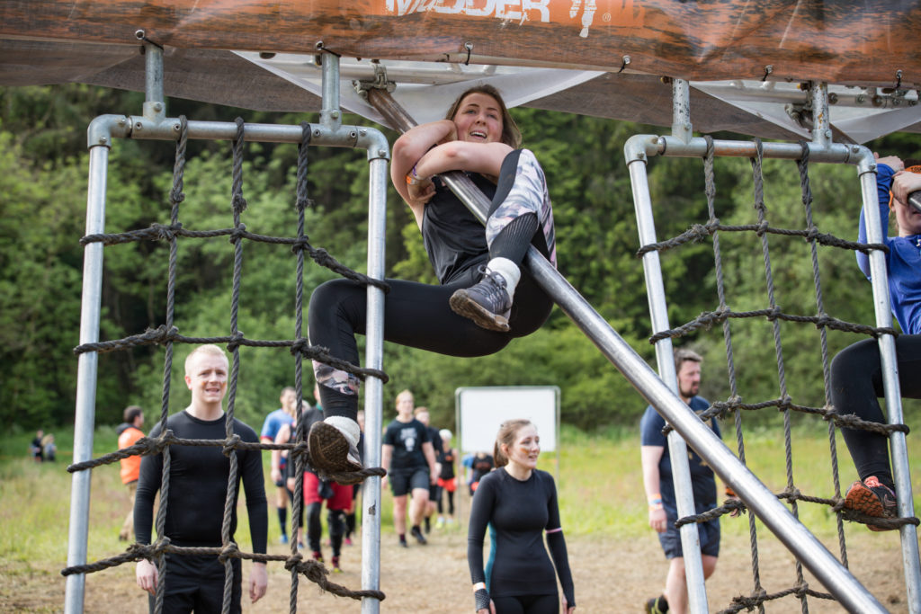 A woman hangs from a slanted metal pole