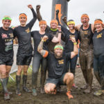 A muddy team of people wearing headbands