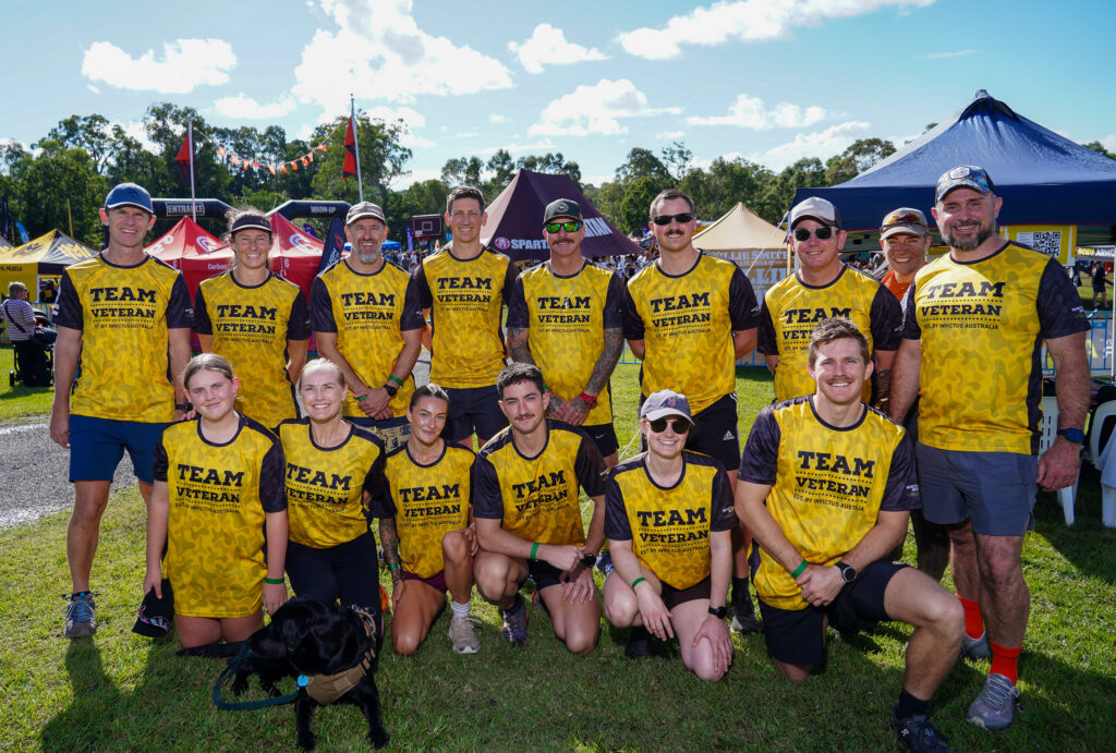 Professional in muddy work gear climbing over a Tough Mudder obstacle